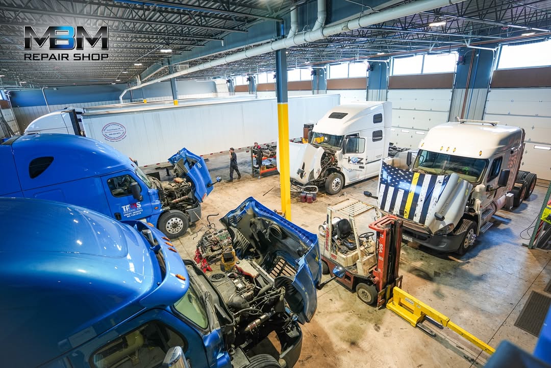 Interior of MBM Repair Shop with semi-trucks being serviced across the bay floor
