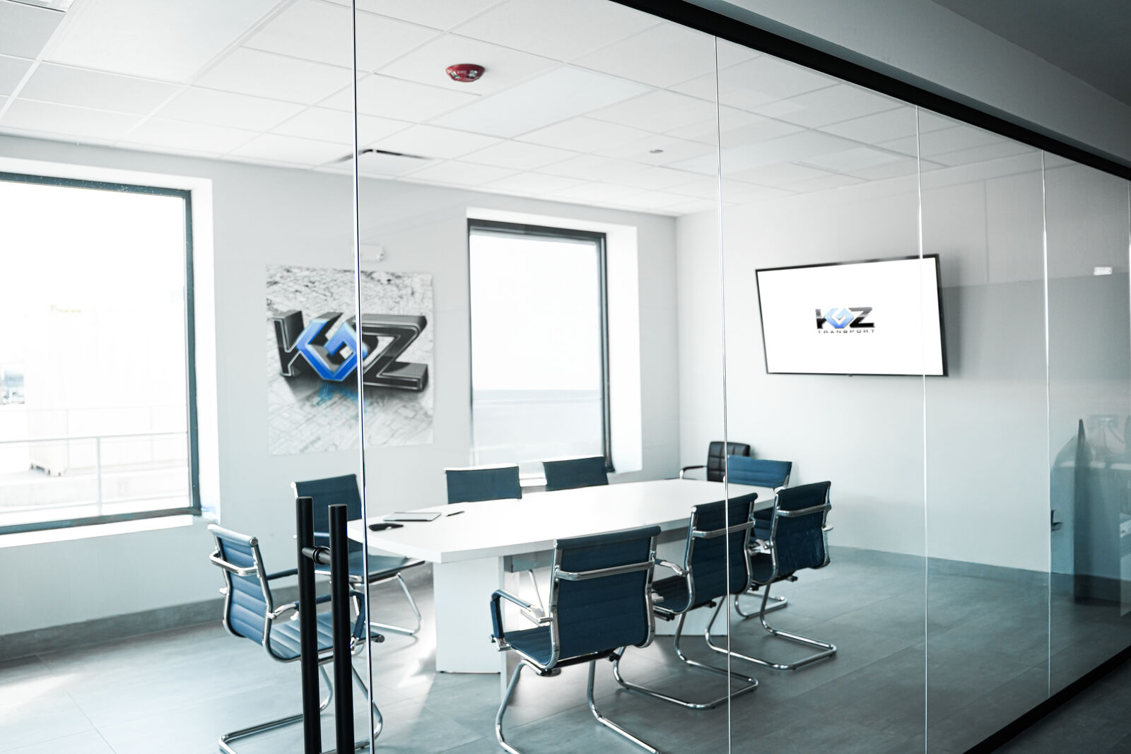 Glass-walled conference room with KGZ Transport logo displayed on a wall-mounted screen